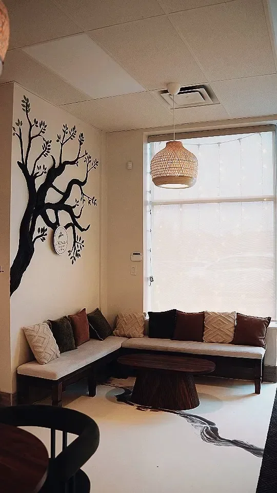 Mithaas Cake & Café: a painted tree on the feature wall, a cushioned corner banquette and a woven pendant light