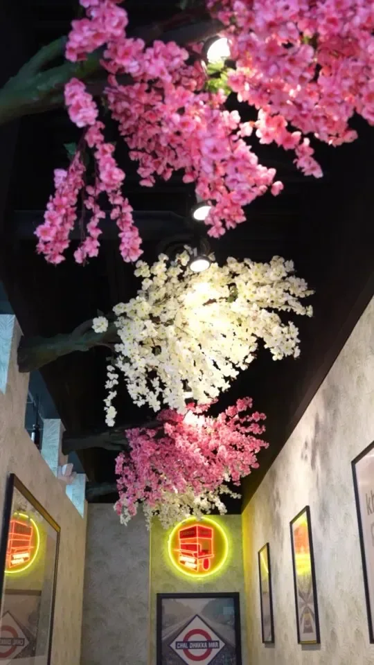 Street Chaat dining room ceiling hung with pink and white blossoms above neon wall signs